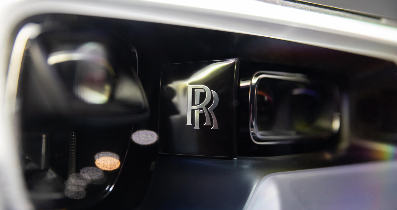 Close-up of a luxury Rolls-Royce Cullinan vehicle's headlight featuring intricate LED design and sleek contours. Available for rental from Realcar Company